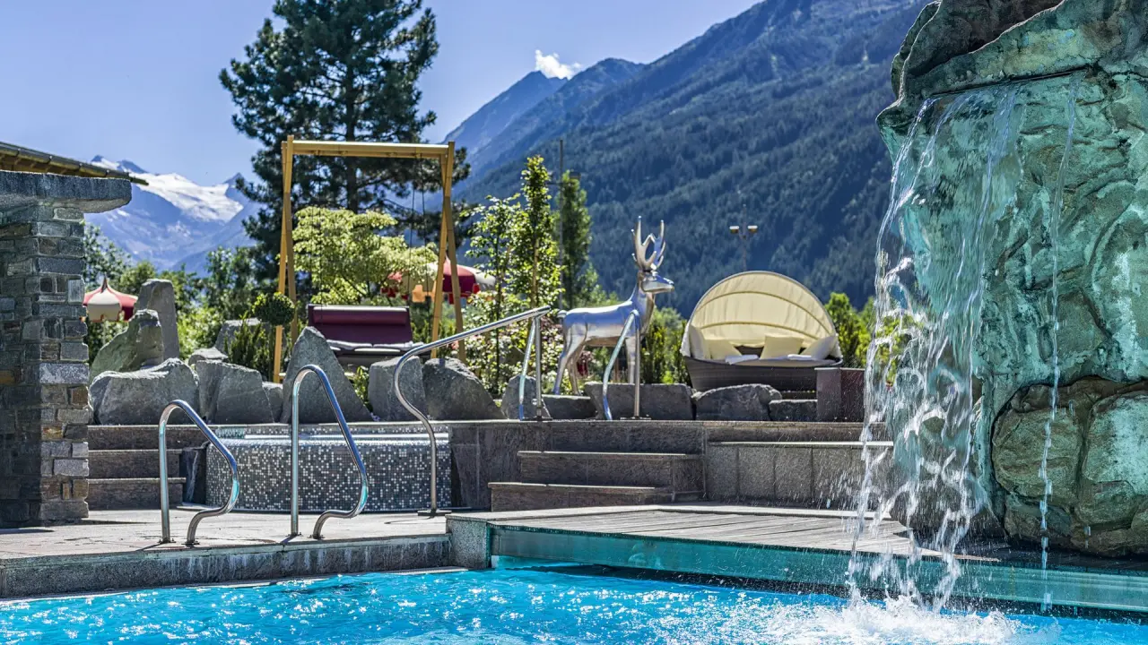Relais & Châteaux Spa Hotel Jagdhof in Neustift im Stubaital – Außenpool mit Wasserfall und Bergblick | Wellnesshotel Stubaital
