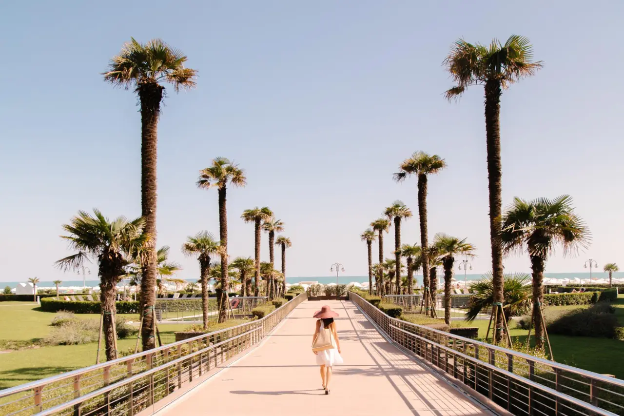 Almar Resort & Spa in Jesolo – Palmenallee zum Strand mit Spaziergängerin | Wellnesshotel Venetien