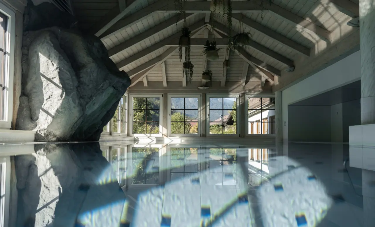 Bergrose Hideaway in Strobl – Innenpool mit Wasserspiegelungen und Holzdecke | Wellnesshotel Salzkammergut