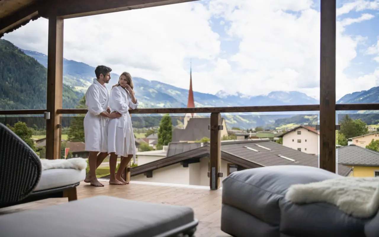 Hotel Wöscherhof in Uderns – Paar in Bademänteln auf dem Balkon mit Bergblick | Wellnesshotel Zillertal