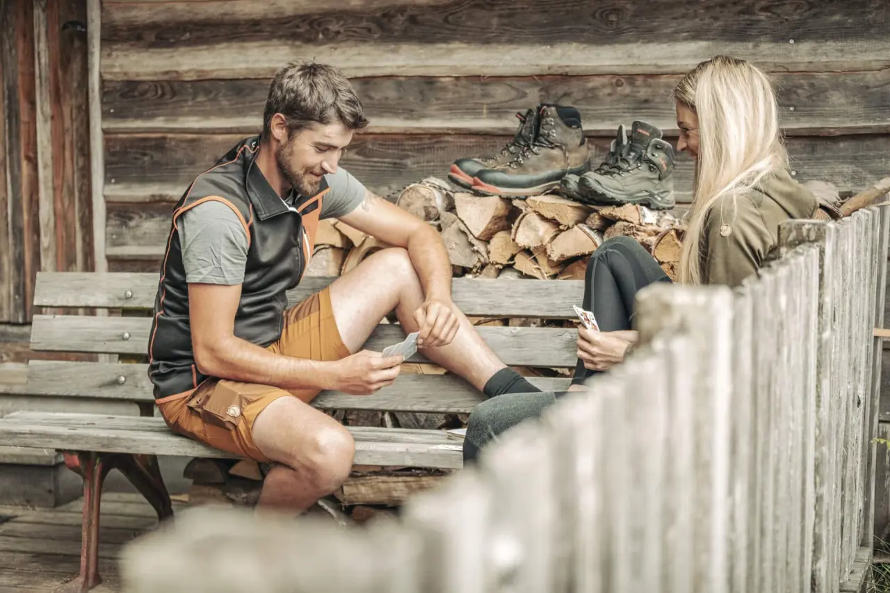 Böhmhof - Wellness- und Vitalhotel in Bodenmais – Paar spielt Karten auf einer Holzbank im Freien | Wellnesshotel Bayerischer Wald