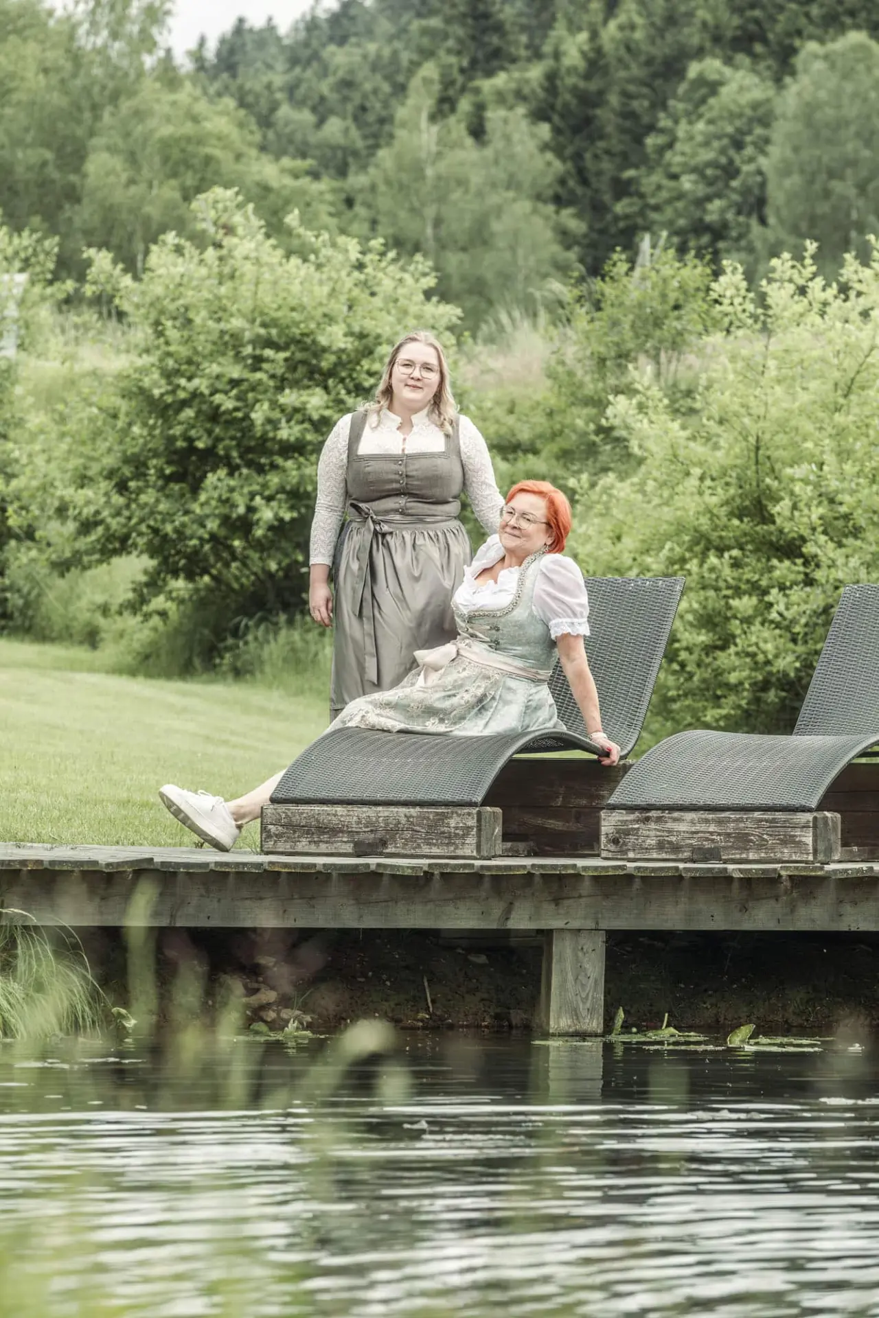 Böhmhof - Wellness- und Vitalhotel in Bodenmais – Frauen in Tracht entspannen am Teich im Garten | Wellnesshotel Bayerischer Wald