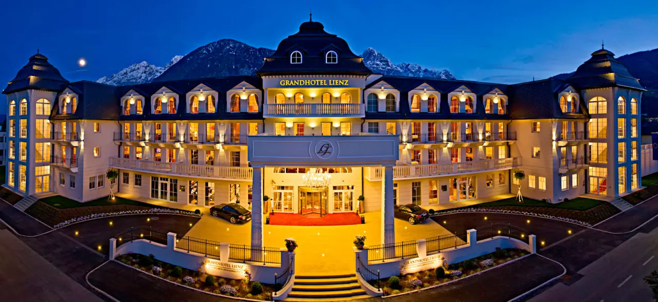 Grandhotel Lienz in Lienz – Beleuchtete Fassade bei Nacht mit Bergsilhouette | Wellnesshotel Osttirol