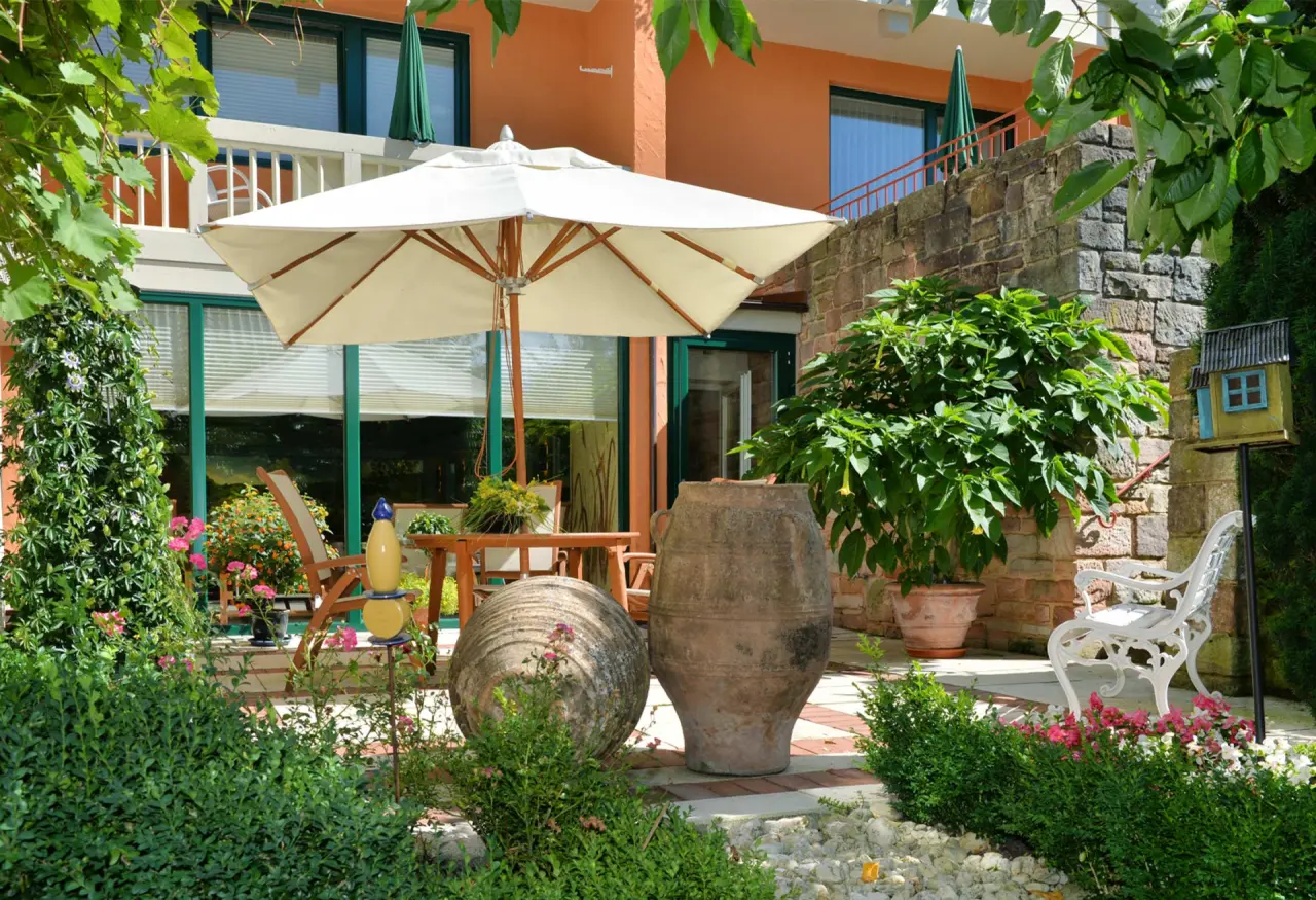 Landhaushotel Hof Wasserkuppe in Poppenhausen – Gartenbereich mit Terrasse und Sonnenschirm | Wellnesshotel Rhön
