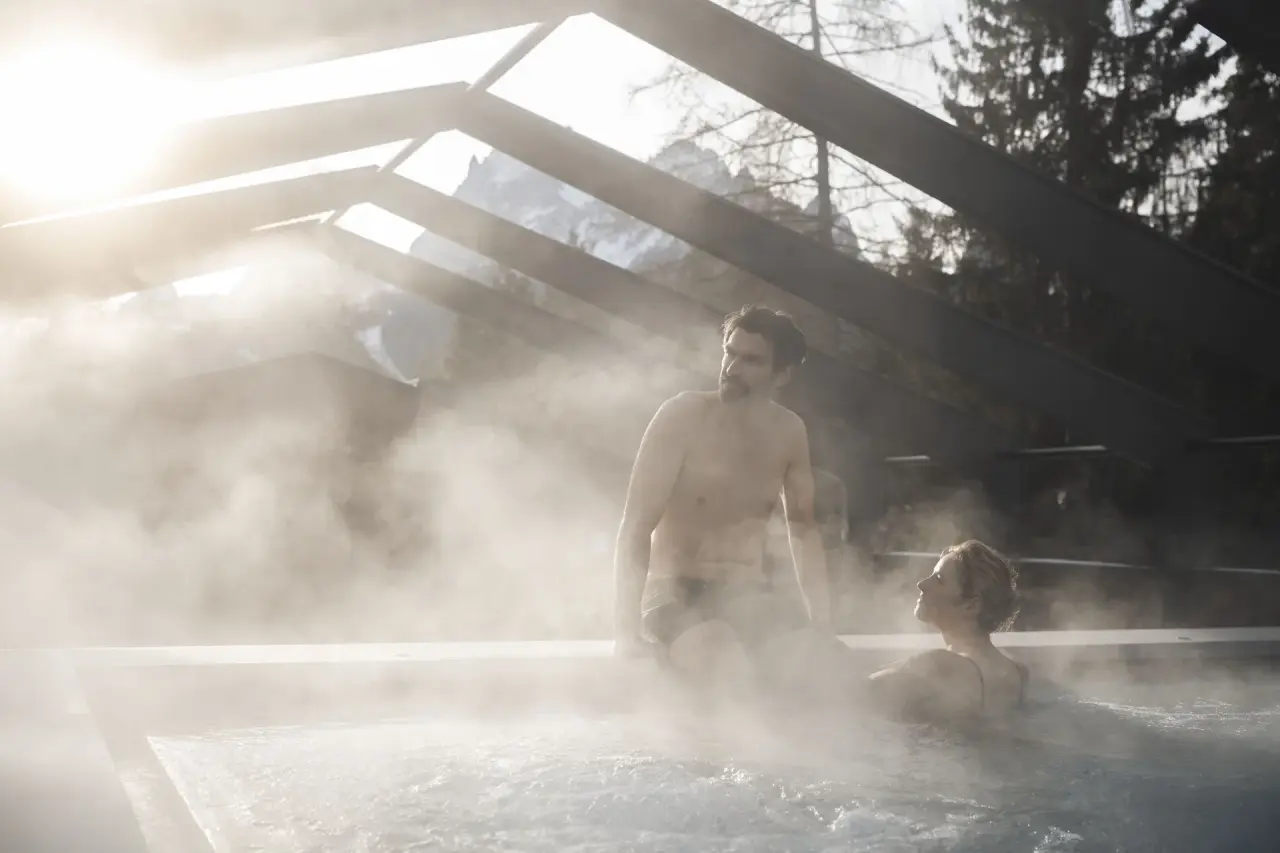 Hotel Monika in Sexten – Paar entspannt im dampfenden Außenpool mit Bergblick | Wellnesshotel Südtirol