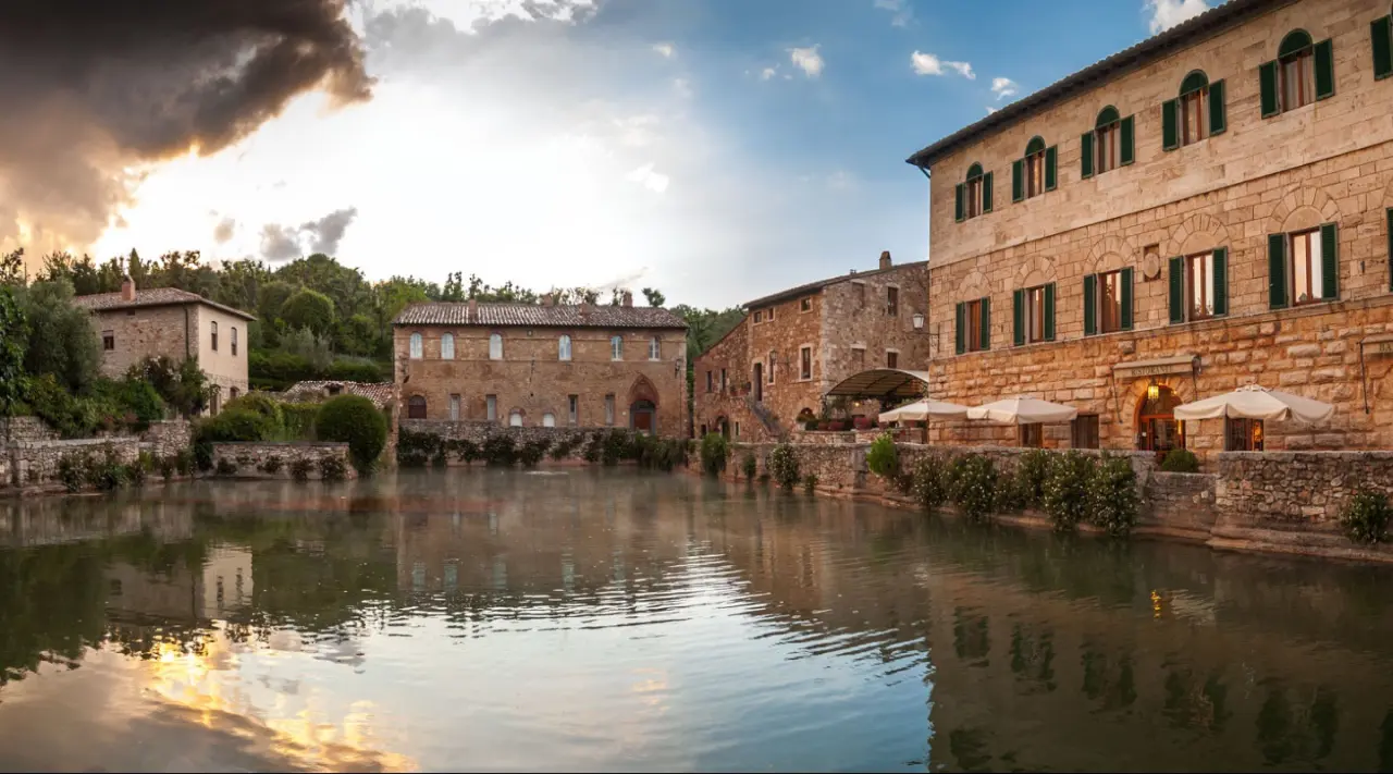 Albergo Le Terme in Bagno Vignoni – Historische Hotelgebäude am Thermalbecken unter dramatischem Himmel | Wellnesshotel Toskana
