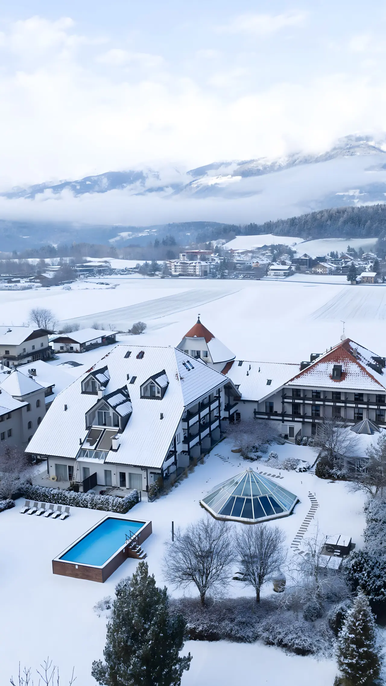 Montis – Active Nature Resort in Bruneck – Hotelanlage im Winter mit Außenpool und Bergen | Wellnesshotel Südtirol