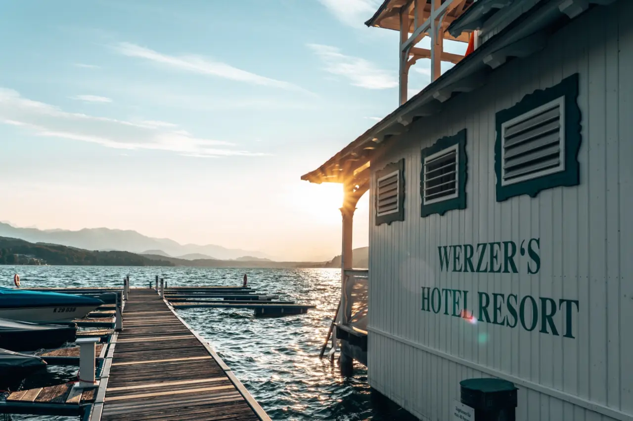Werzers Hotel Resort Pörtschach in Pörtschach – Bootssteg und Hotelgebäude am Wörthersee bei Sonnenuntergang | Wellnesshotel Wörthersee