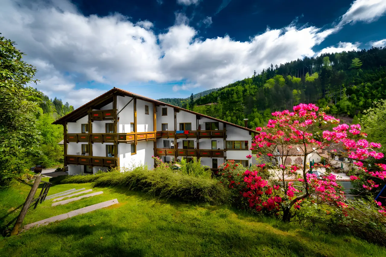 Holzschuh’s Schwarzwaldhotel in Baiersbronn – Hotelgebäude im Grünen mit blühenden Rhododendren | Wellnesshotel Schwarzwald