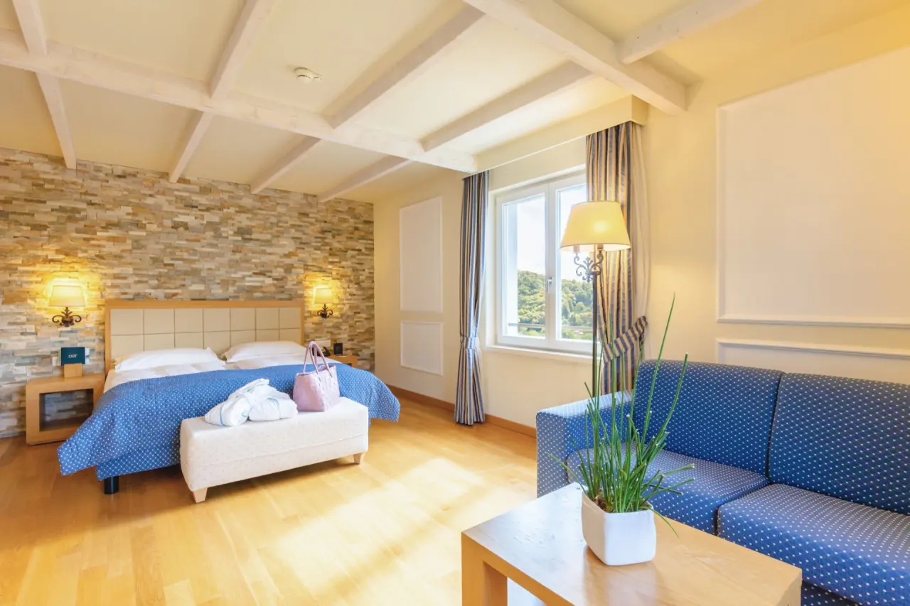 Kurhaus Cademario in Cademario – Komfortables Doppelzimmer mit Steinwand und Sofa | Wellnesshotel Tessin