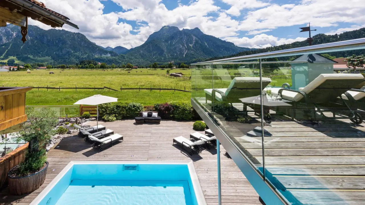 Das Rübezahl in Schwangau – Sonniger Poolbereich mit Liegen und Bergblick | Wellnesshotel Allgäu