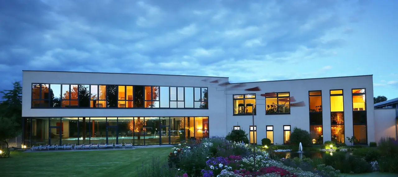 See Park Janssen in Geldern – Hotelgebäude bei Dämmerung mit beleuchtetem Garten | Wellnesshotel Niederrhein