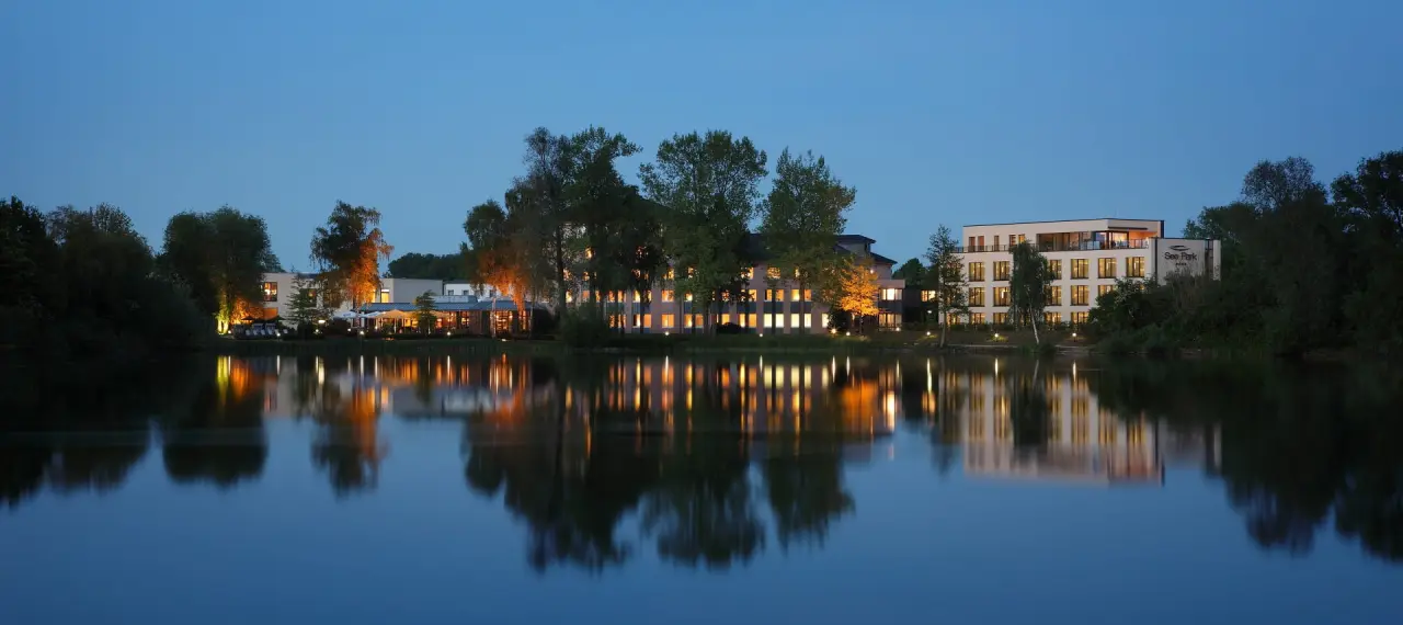 See Park Janssen in Geldern – Hotelansicht bei Nacht mit Spiegelung im See | Wellnesshotel Niederrhein