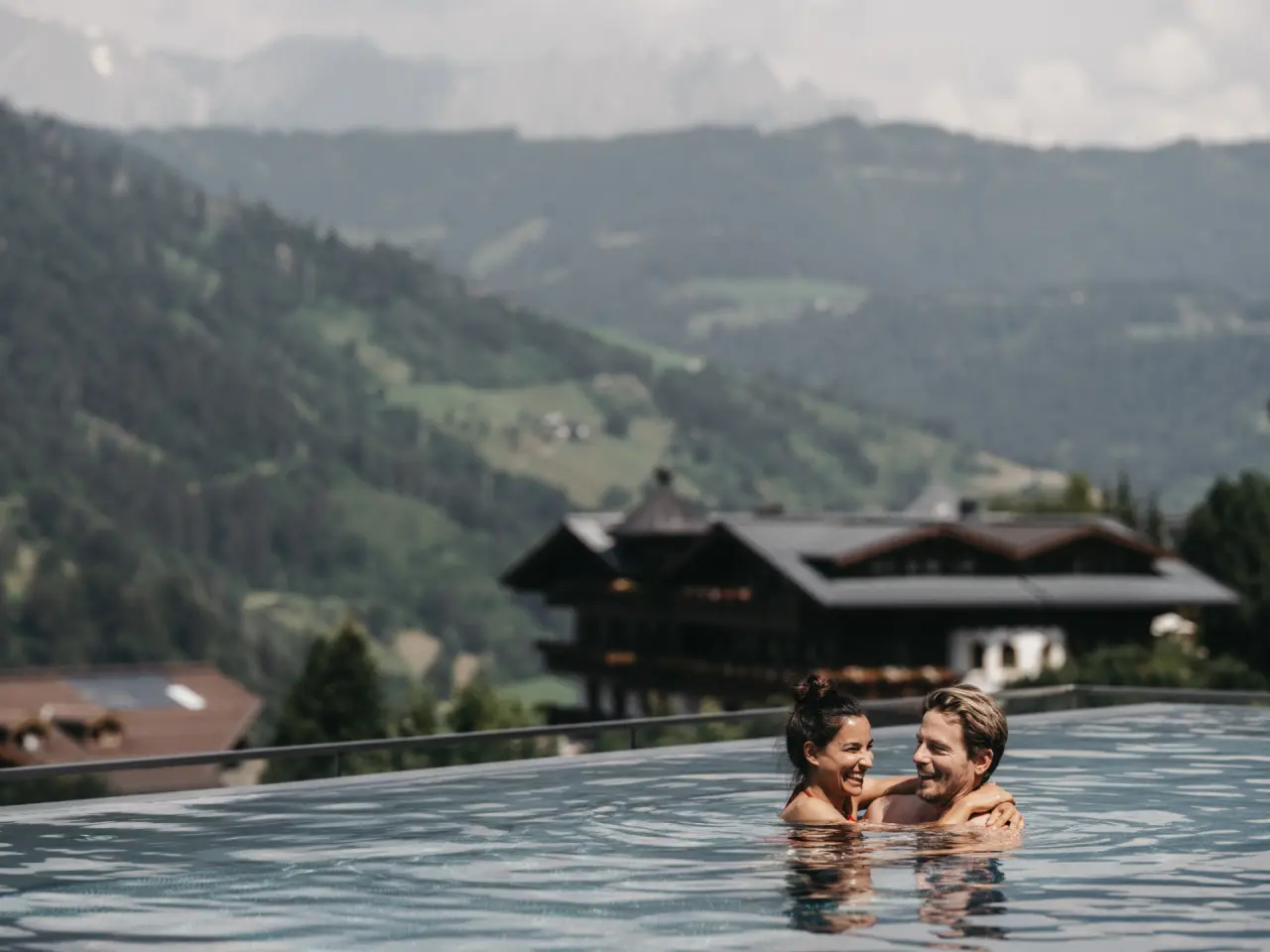 Alpina Alpendorf in St. Johann im Pongau – Paar im Infinity-Pool mit Alpenpanorama | Wellnesshotel Salzburger Land