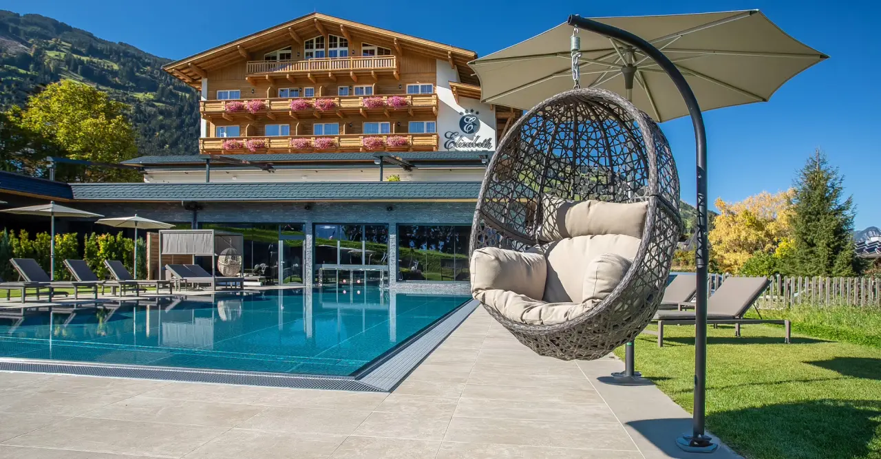 Hotel Elisabeth in Fügen – Außenpool mit Hotelgebäude und Bergkulisse | Wellnesshotel Zillertal