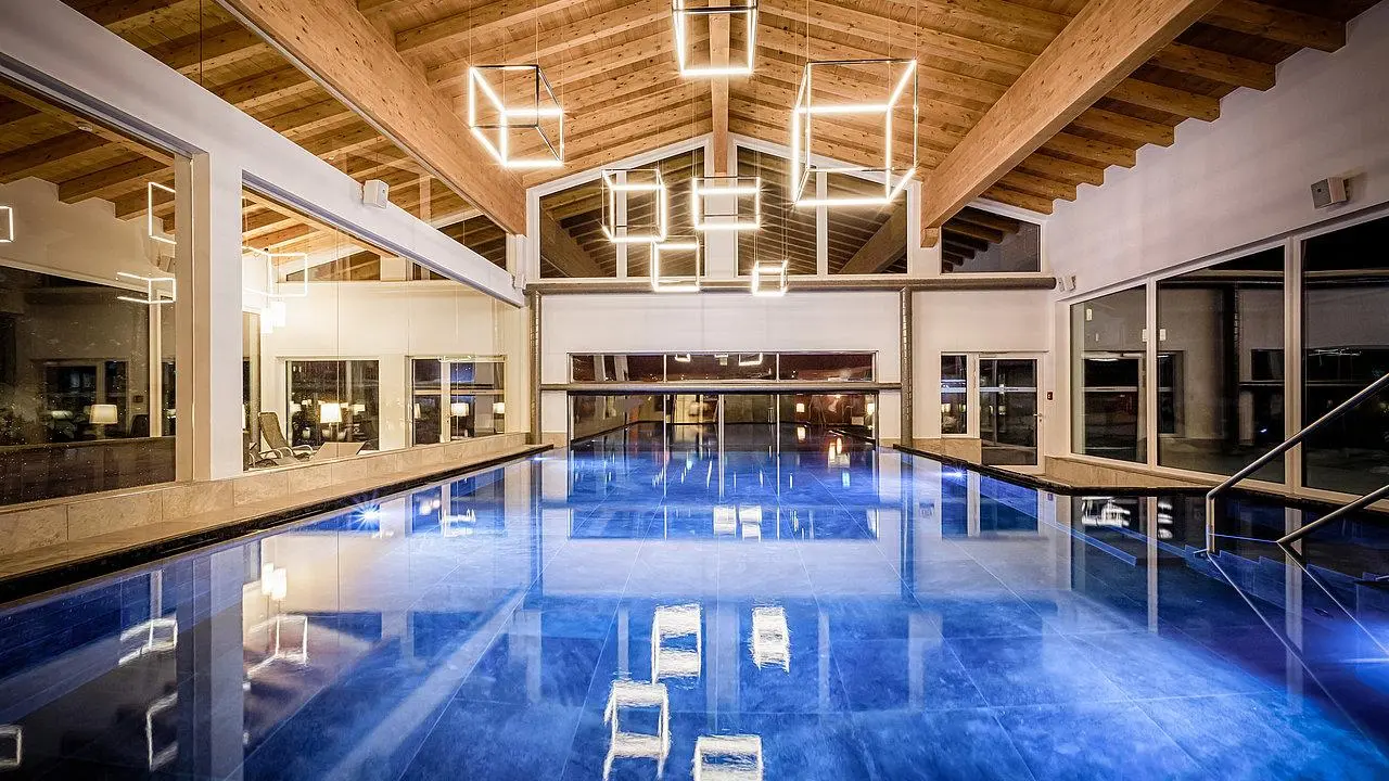 Das Walchsee Sportresort in Walchsee – Moderner Innenpool mit Holzdach und Designleuchten | Wellnesshotel Tirol