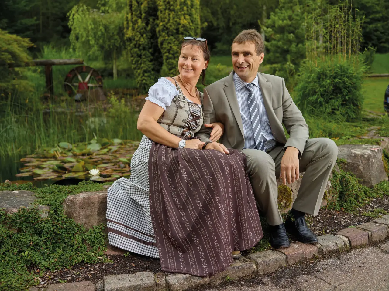 Hotel Waldsägmühle in Pfalzgrafenweiler-Kälberbronn – Paar in Tracht am Teich im Hotelgarten | Wellnesshotel Schwarzwald