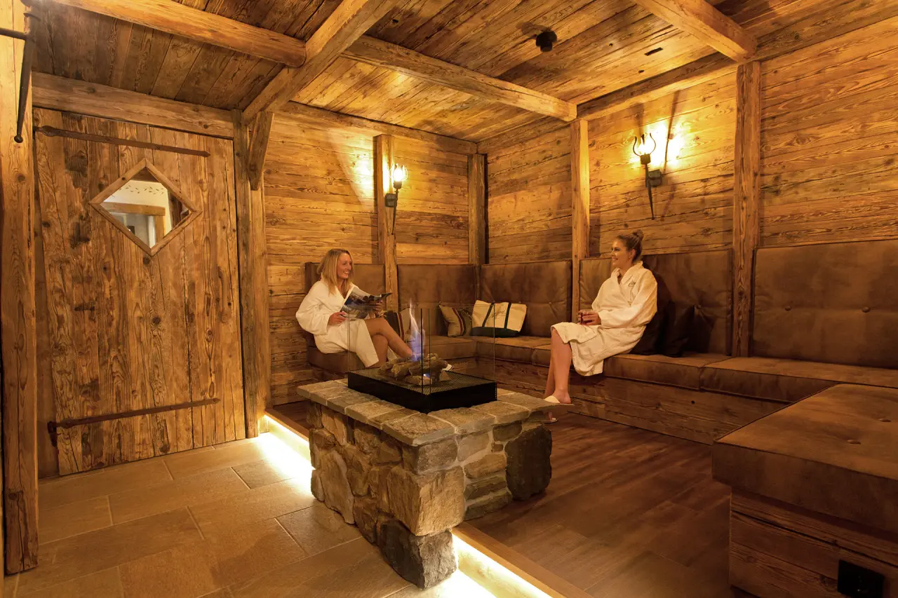 Alm- & Wellnesshotel Alpenhof in Schönau am Königssee – Gemütlicher Ruhebereich mit Kamin und Gästen | Wellnesshotel Berchtesgadener Land