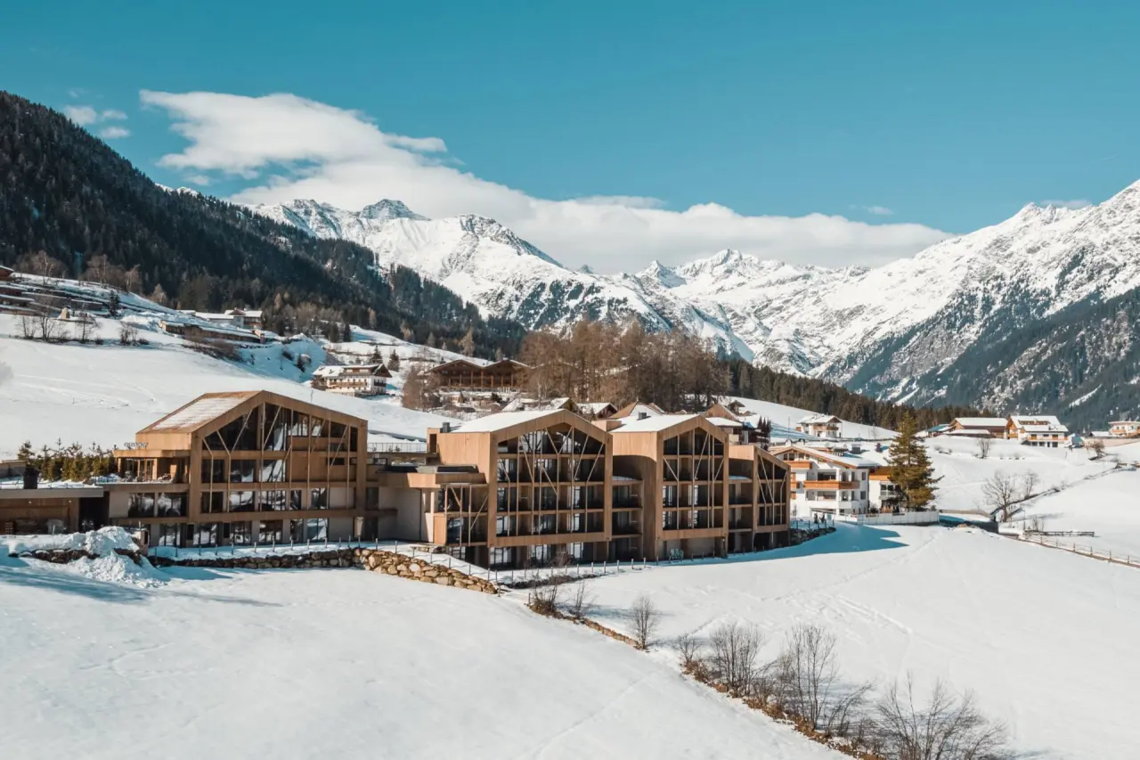 Erlebnisort Gassenhof in Ridnaun / Racines – Hotelgebäude im Winter mit verschneiten Bergen | Wellnesshotel Südtirol