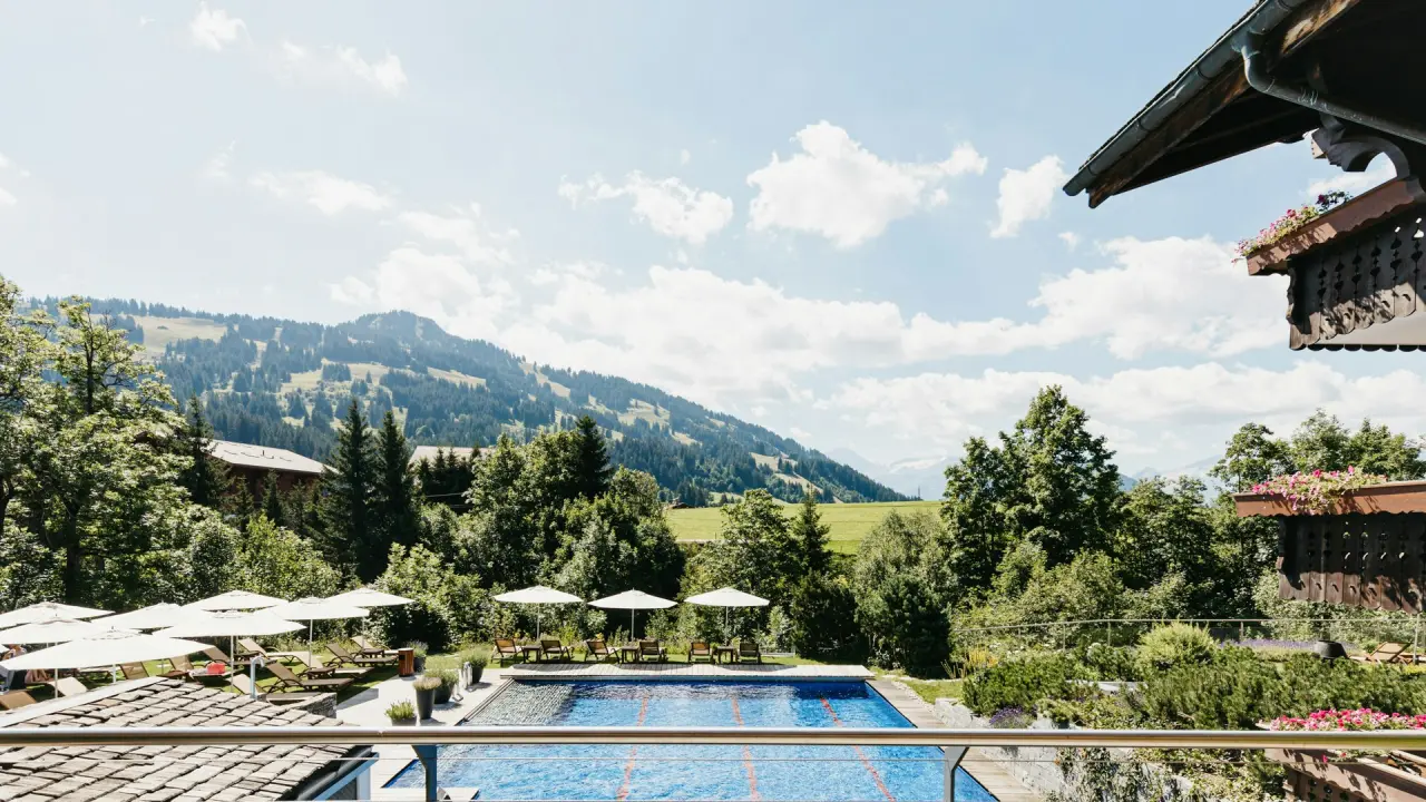 ERMITAGE Wellness- & Spa-Hotel in Gstaad – Sommerlicher Außenbereich mit Pool und Liegen | Wellnesshotel Berner Oberland