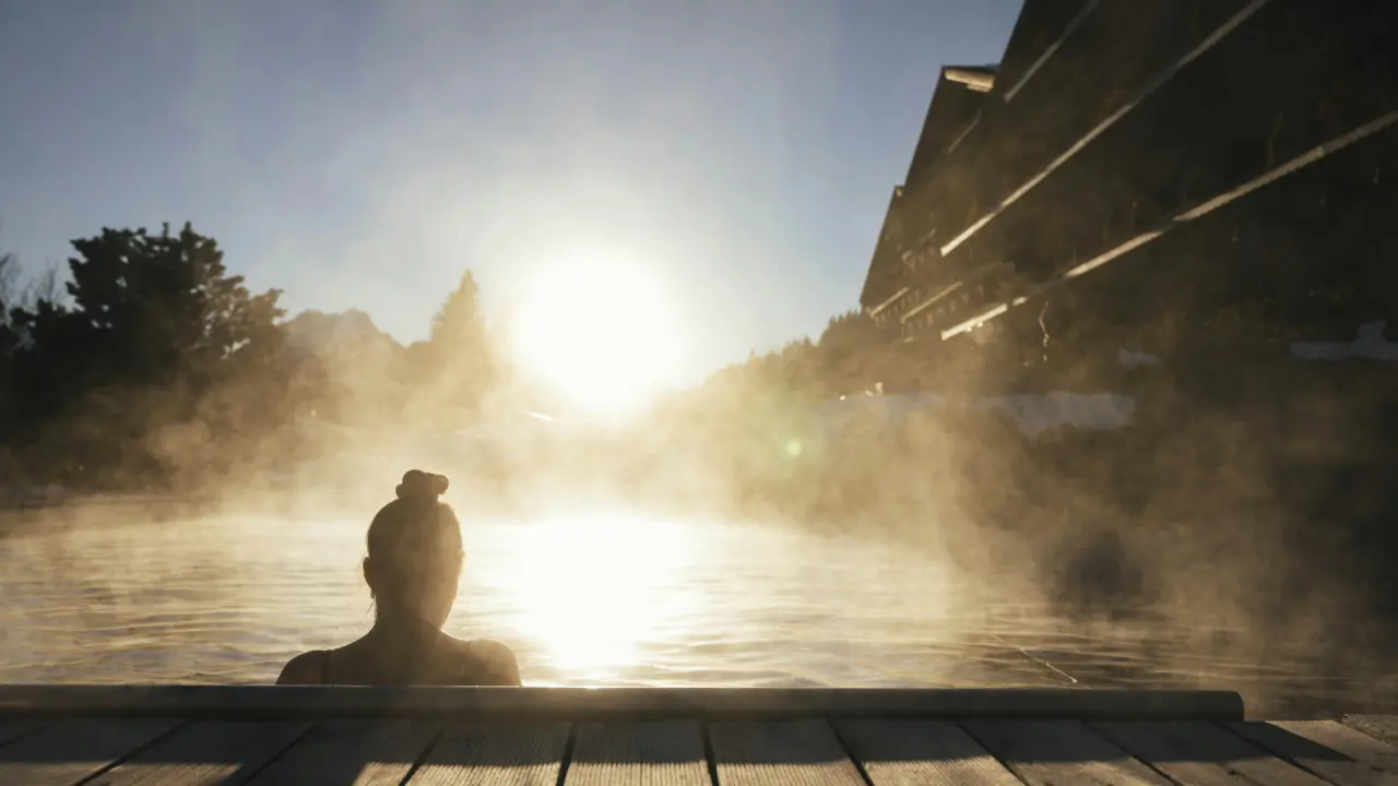 ERMITAGE Wellness- & Spa-Hotel in Gstaad – Dampfender Außenpool bei Sonnenuntergang | Wellnesshotel Berner Oberland
