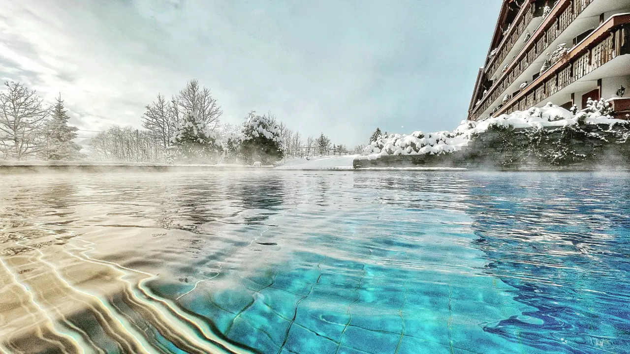 ERMITAGE Wellness- & Spa-Hotel in Gstaad – Dampfender Infinity-Außenpool im Winter | Wellnesshotel Berner Oberland