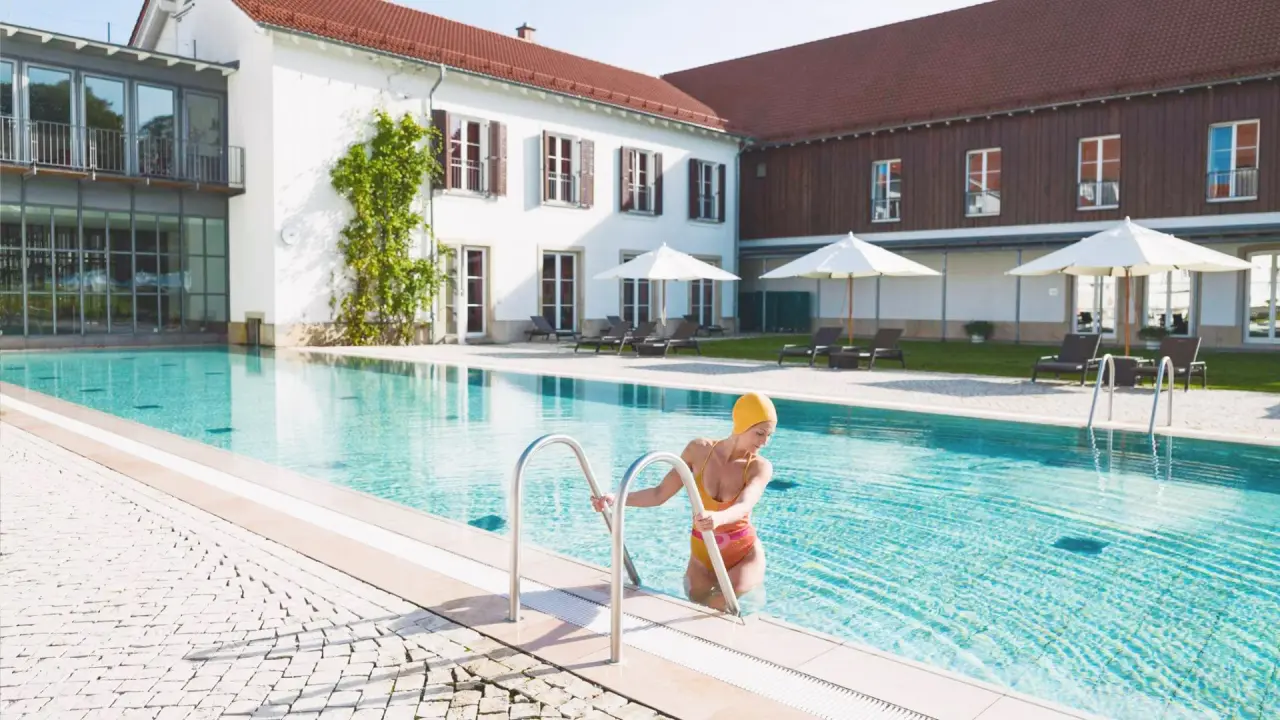 Gräﬂicher Park Health & Balance Resort in Bad Driburg – Außenpool mit Gast und historischer Architektur | Wellnesshotel Teutoburger Wald