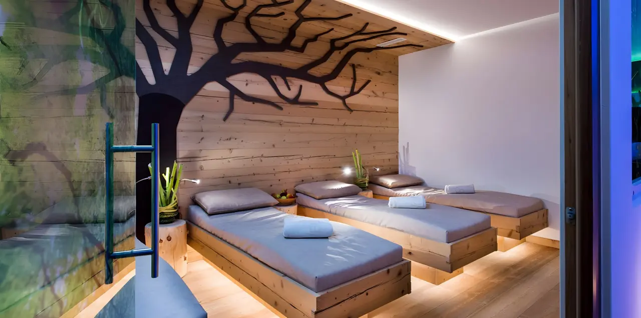 Abinea Dolomiti Romantic SPA Hotel in Kastelruth – Entspannungsraum mit Holzliegen und Baumdekor | Wellnesshotel Südtirol