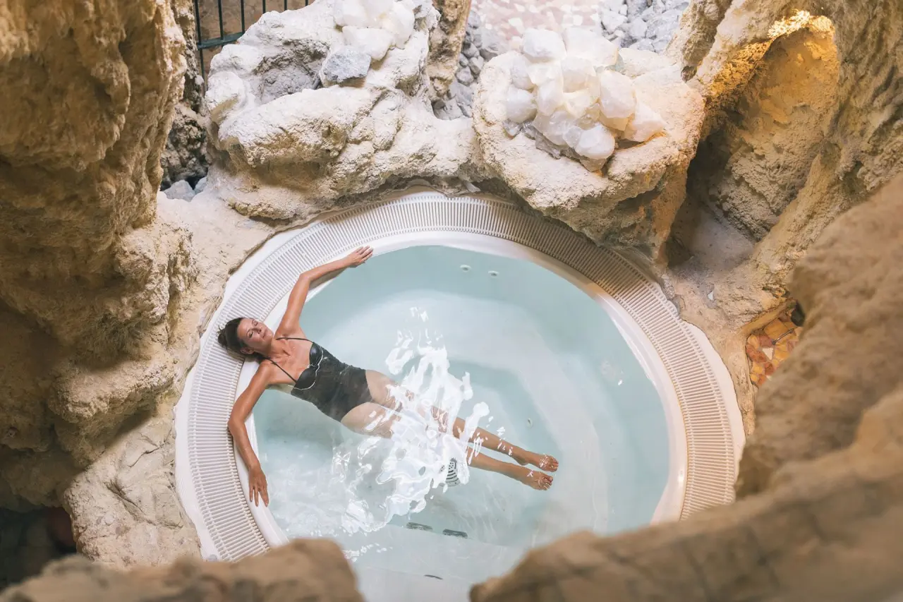 Wellnesshotel ...liebes Rot-Flüh in Grän – Frau entspannt im Whirlpool in Felsengrotte | Wellnesshotel Tirol