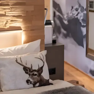 La Val Hotel & Spa in Brigels – Gemütliches Bett mit Hirschkissen in einem Hotelzimmer | Wellnesshotel Graubünden