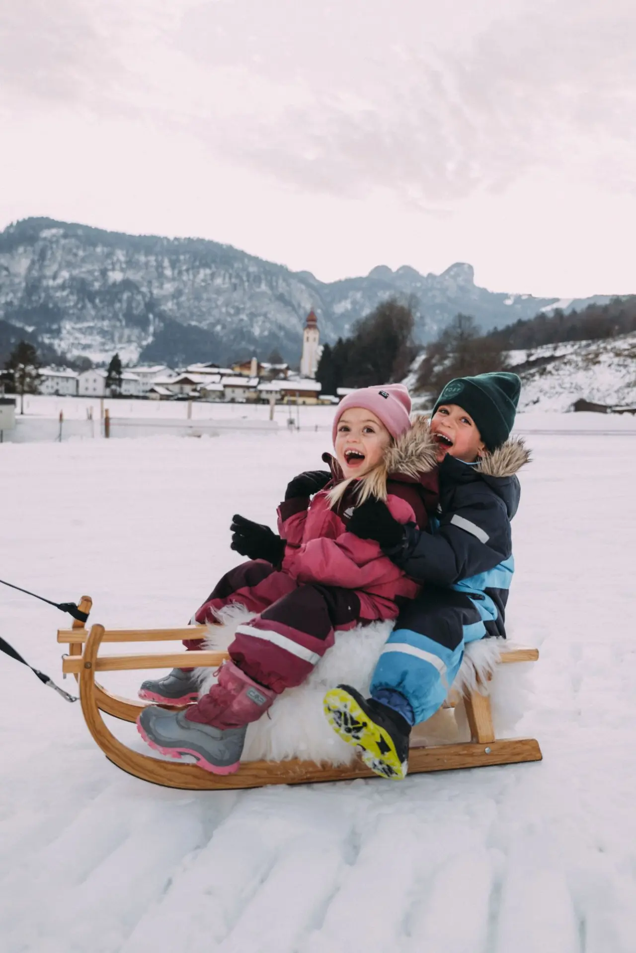 POST Family Resort in Unken – Kinder fahren Schlitten im Schnee mit Bergkulisse | Wellnesshotel Salzburger Land