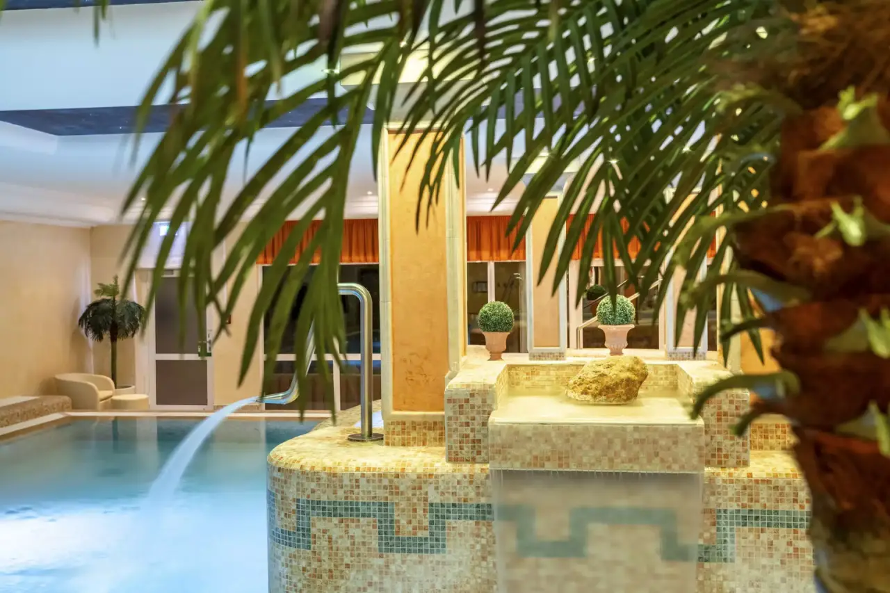 Hotel Schweizer Hof Betriebs-GmbH in Bad Füssing – Innenpoolbereich mit Wasserfall und tropischer Dekoration | Wellnesshotel Bayern