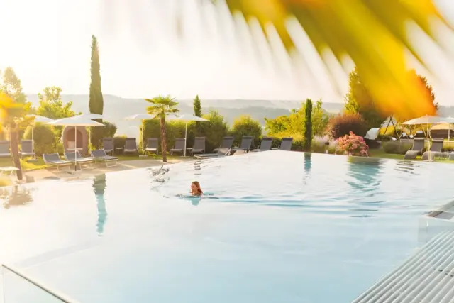 Hotel Larimar in Stegersbach – Frau schwimmt im Infinity-Außenpool mit sonniger Landschaft | Wellnesshotel Burgenland