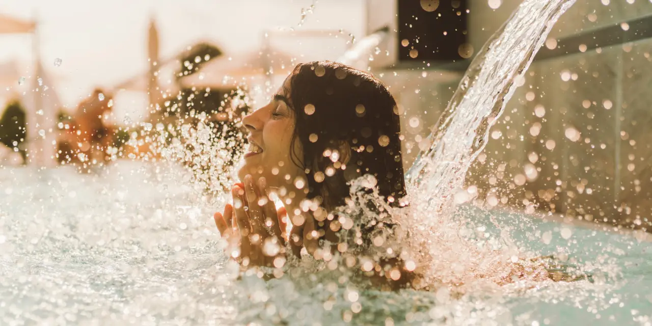Hotel Reiters Supreme in Bad Tatzmannsdorf – Frau genießt Wasserstrahl im Pool | Wellnesshotel Burgenland