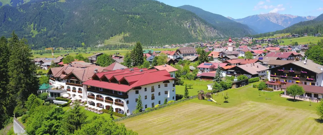 Hotel Alpen Residence in Ehrwald – Luftaufnahme des Hotels und des Dorfes mit Berglandschaft | Wellnesshotel Tirol