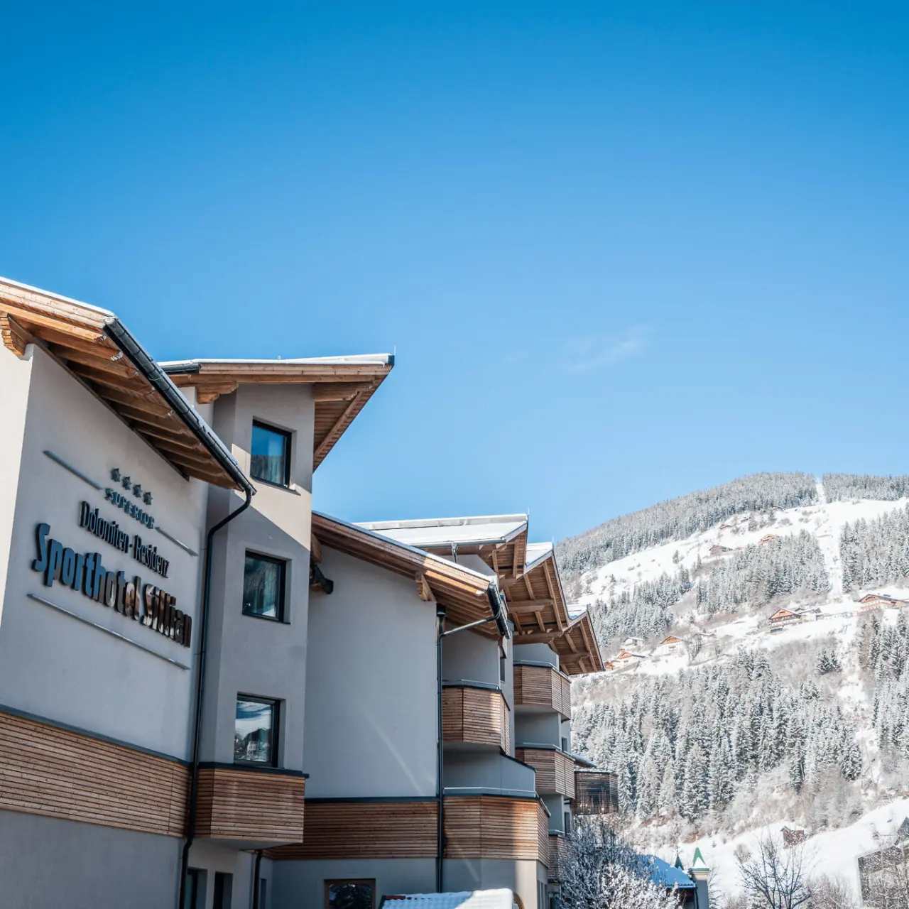 Dolomiten Residenz Sporthotel Sillian in Sillian – Hotelgebäude mit Schriftzug und verschneiter Landschaft | Wellnesshotel Osttirol
