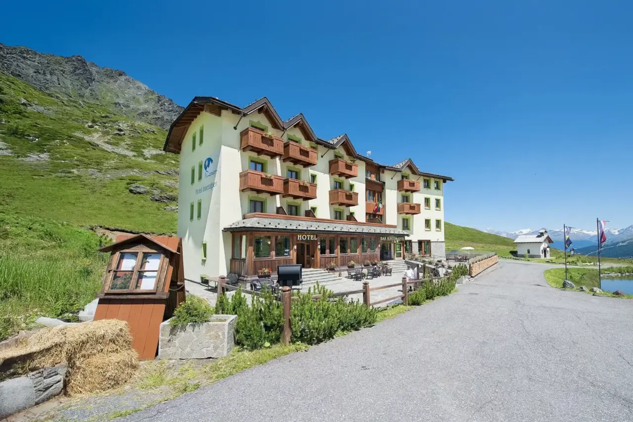 Hotel Interalpen - Mountain Resort in Livigno – Hotelgebäude im Sommer mit grünen Wiesen | Wellnesshotel Alpen