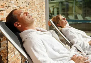 Hotel Eden Spiez in Spiez – Paar entspannt auf Sonnenliegen im Garten | Wellnesshotel Berner Oberland