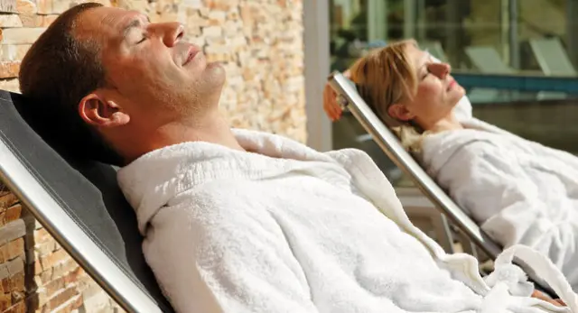 Hotel Eden Spiez in Spiez – Paar entspannt in Bademänteln auf Liegen im Wellnessbereich | Wellnesshotel Berner Oberland