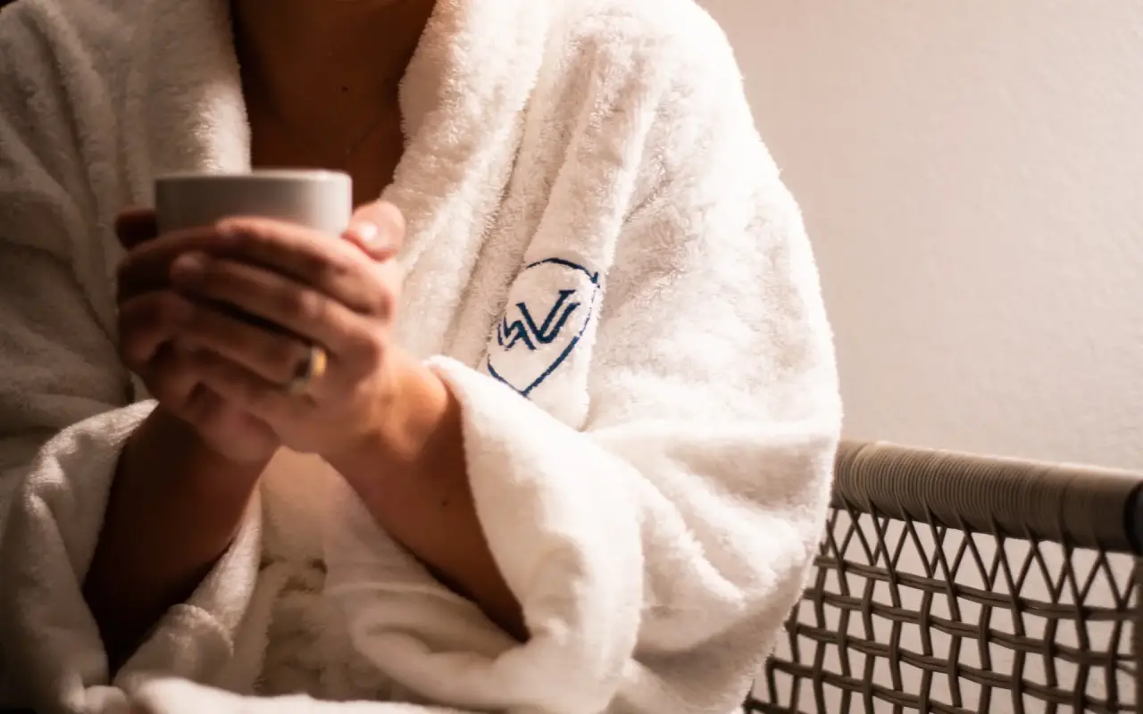Walliserhof Grand-Hotel & Spa in Saas-Fee – Gast im Bademantel mit Hotel-Logo und Tasse | Wellnesshotel Wallis