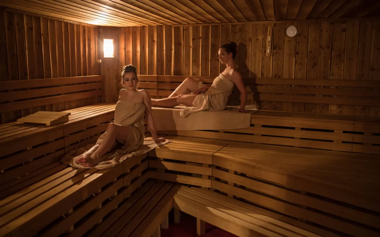 Walliserhof Grand-Hotel & Spa in Saas-Fee – Geräumige Holzsauna mit entspannenden Gästen | Wellnesshotel Wallis