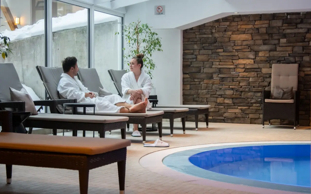 Walliserhof Grand-Hotel & Spa in Saas-Fee – Entspannungsbereich am Pool mit Liegen und Gästen | Wellnesshotel Wallis