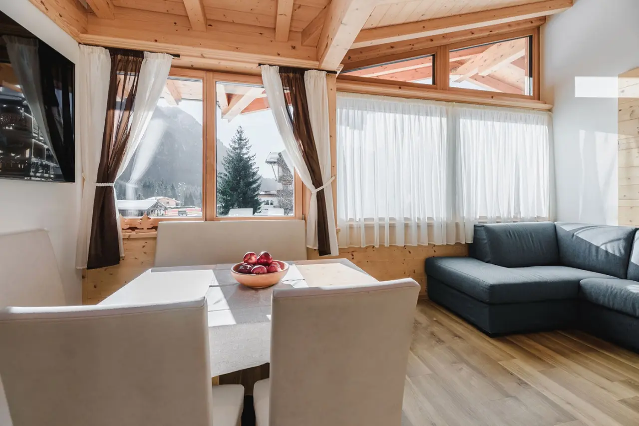 Césa Edelweiss Living & Spa Fassa in Campitello di Fassa – Wohnbereich mit Bergblick und Esstisch | Wellnesshotel Fassa