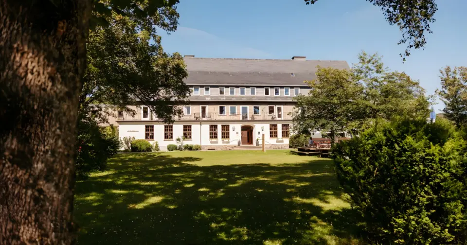 Berghotel Hoher Knochen in Schmallenberg – Hotelgebäude am Tag, umgeben von grünen Bäumen | Wellnesshotel Sauerland