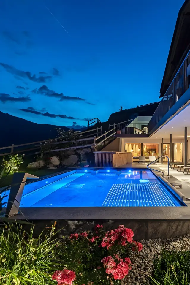 Hotel Torgglerhof bei Brixen in Brixen – Beleuchteter Außenpool bei Nacht mit Bergblick | Wellnesshotel Südtirol