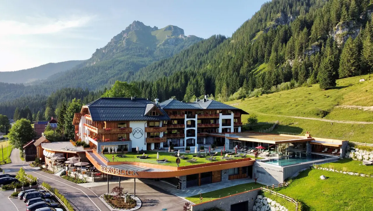 Hotel Bergblick in Grän – Panoramablick auf das Hotel mit Außenpool und Bergkulisse im Sommer | Wellnesshotel Tannheimer Tal