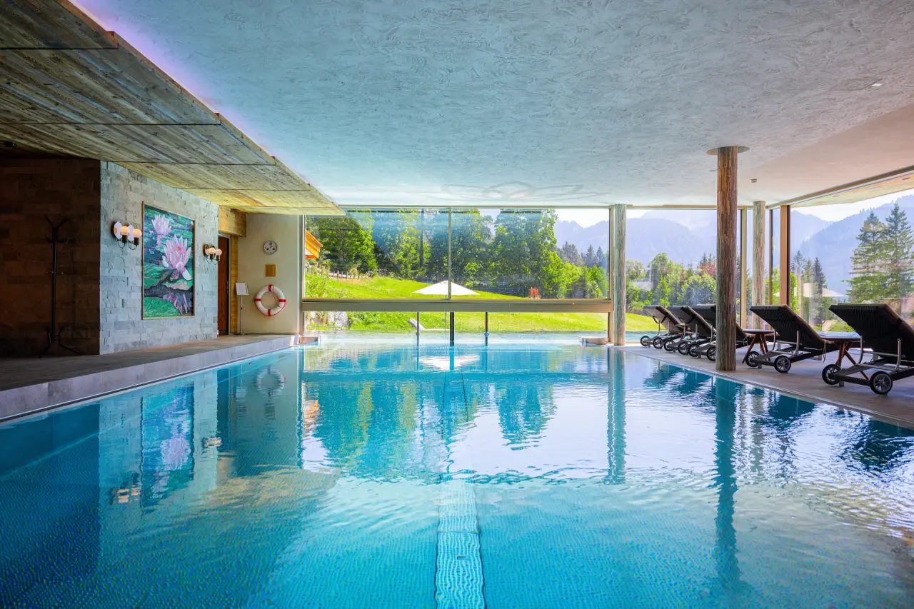 Hotel Bergblick in Grän – Heller Innenpool mit Panoramafenstern und Blick auf die grüne Natur | Wellnesshotel Tannheimer Tal