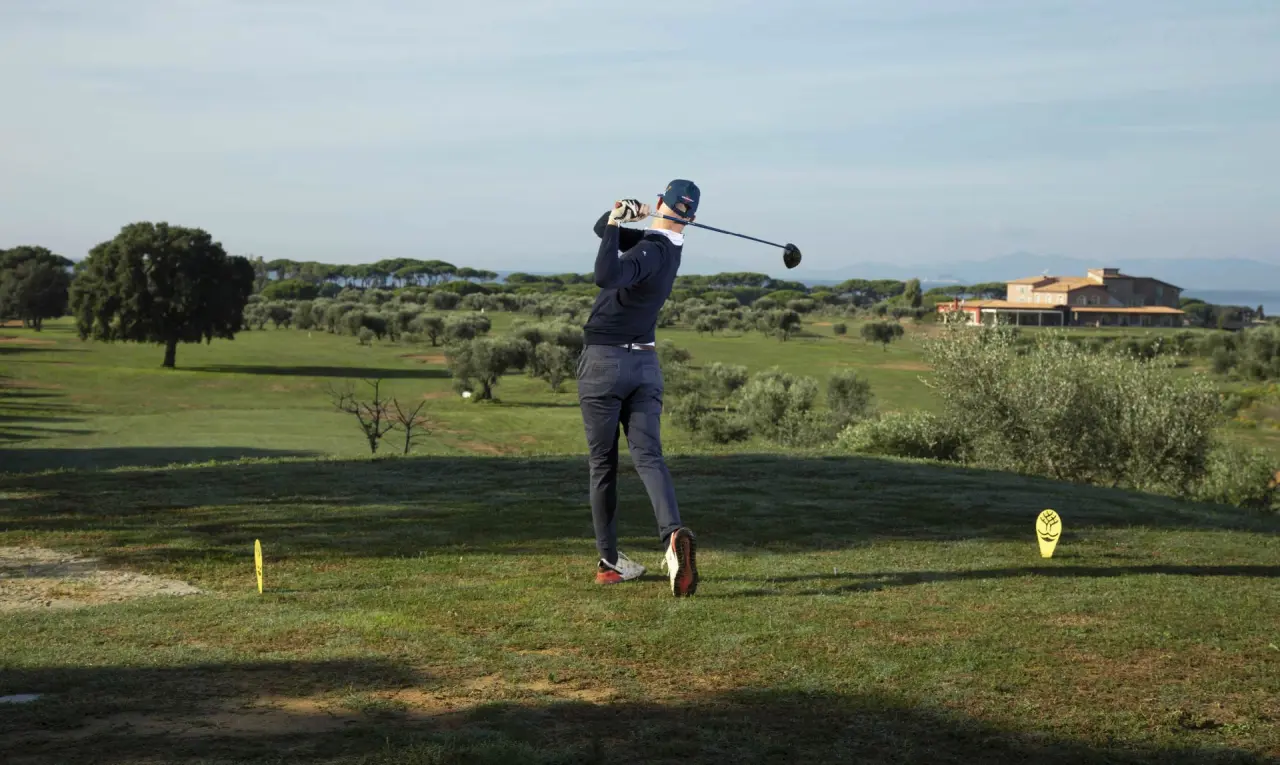 Riva Toscana Golf Resort & SPA in Follonica – Golfer auf dem Golfplatz mit Hotel im Hintergrund | Wellnesshotel Toskana