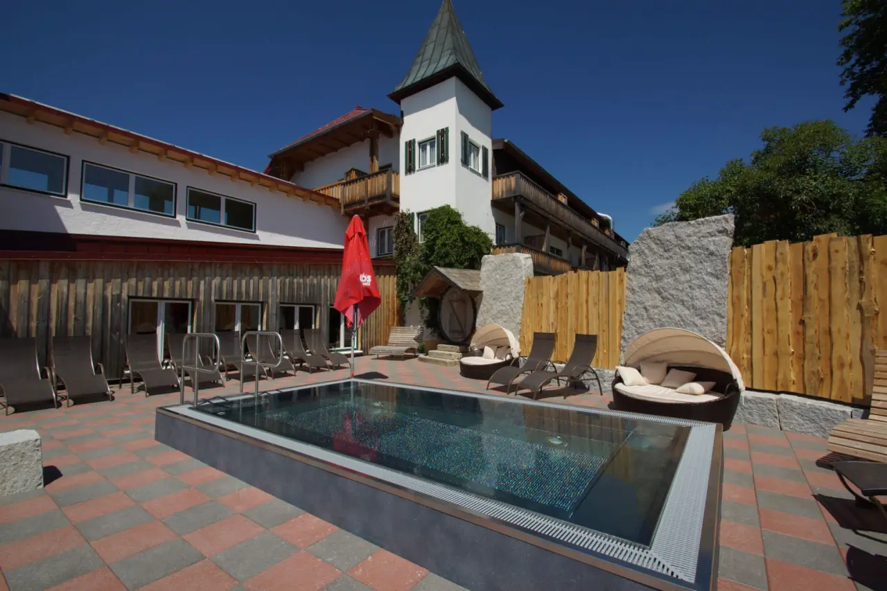 Bier- und Wohlfühlhotel Gut Riedelsbach in Neureichenau – Außenpool mit Liegebereich und Hotelansicht | Wellnesshotel Bayerischer Wald