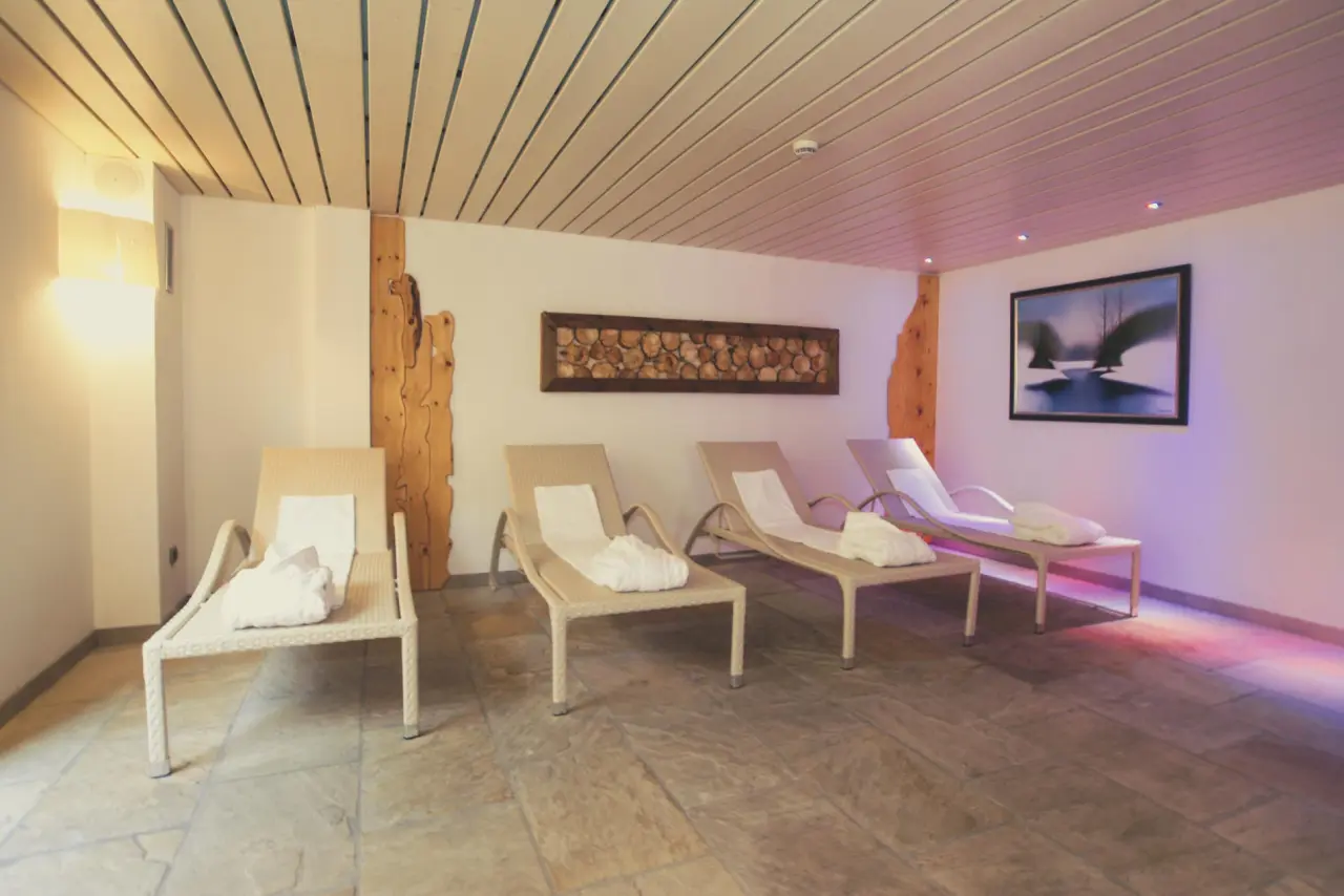 THE SUN Hotel Resort Clubresidence in Canazei – Entspannender Ruheraum mit Liegen und indirekter Beleuchtung | Wellnesshotel Dolomiten